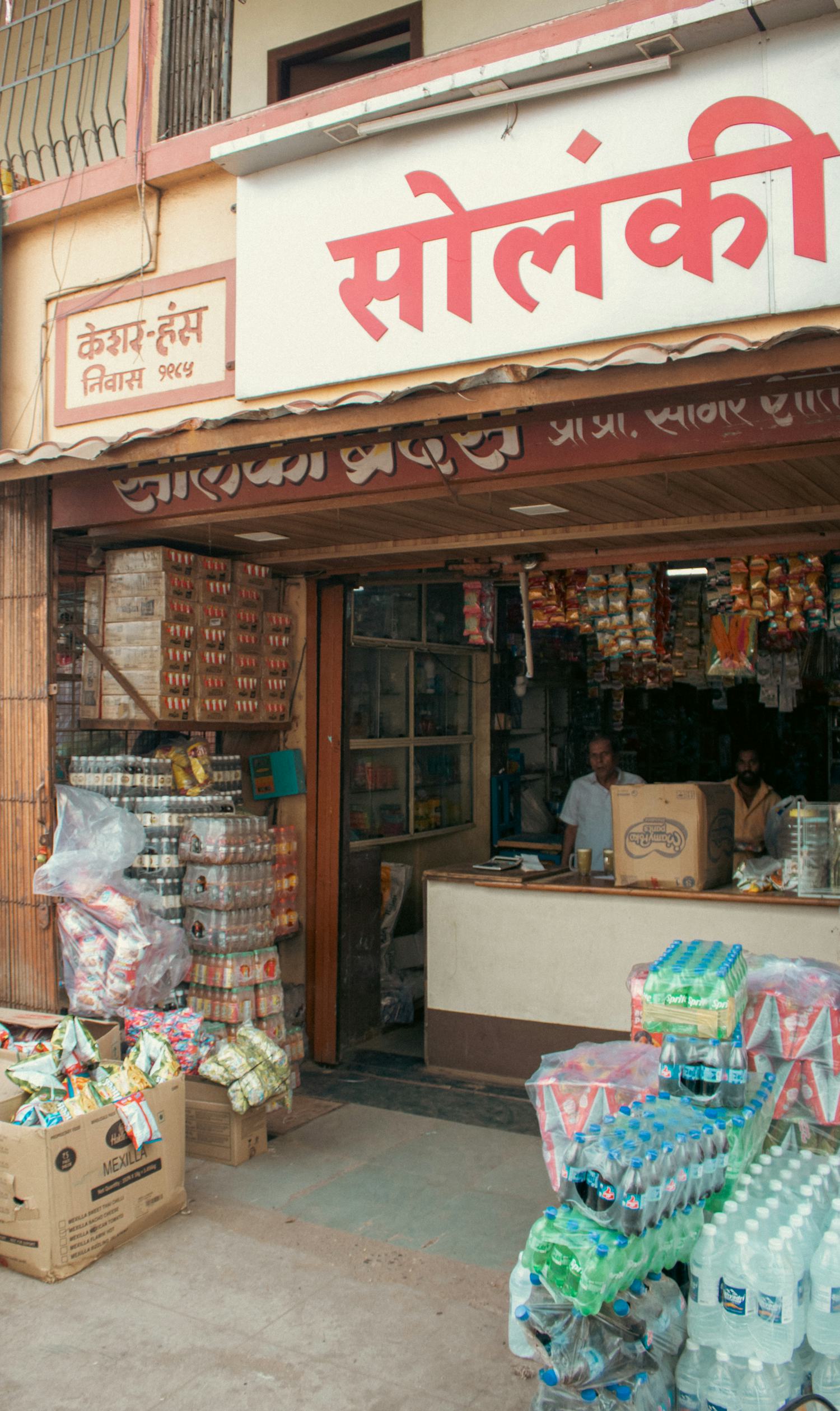 A neighbourhood kirana shopfront with goods on display and Hindi signage